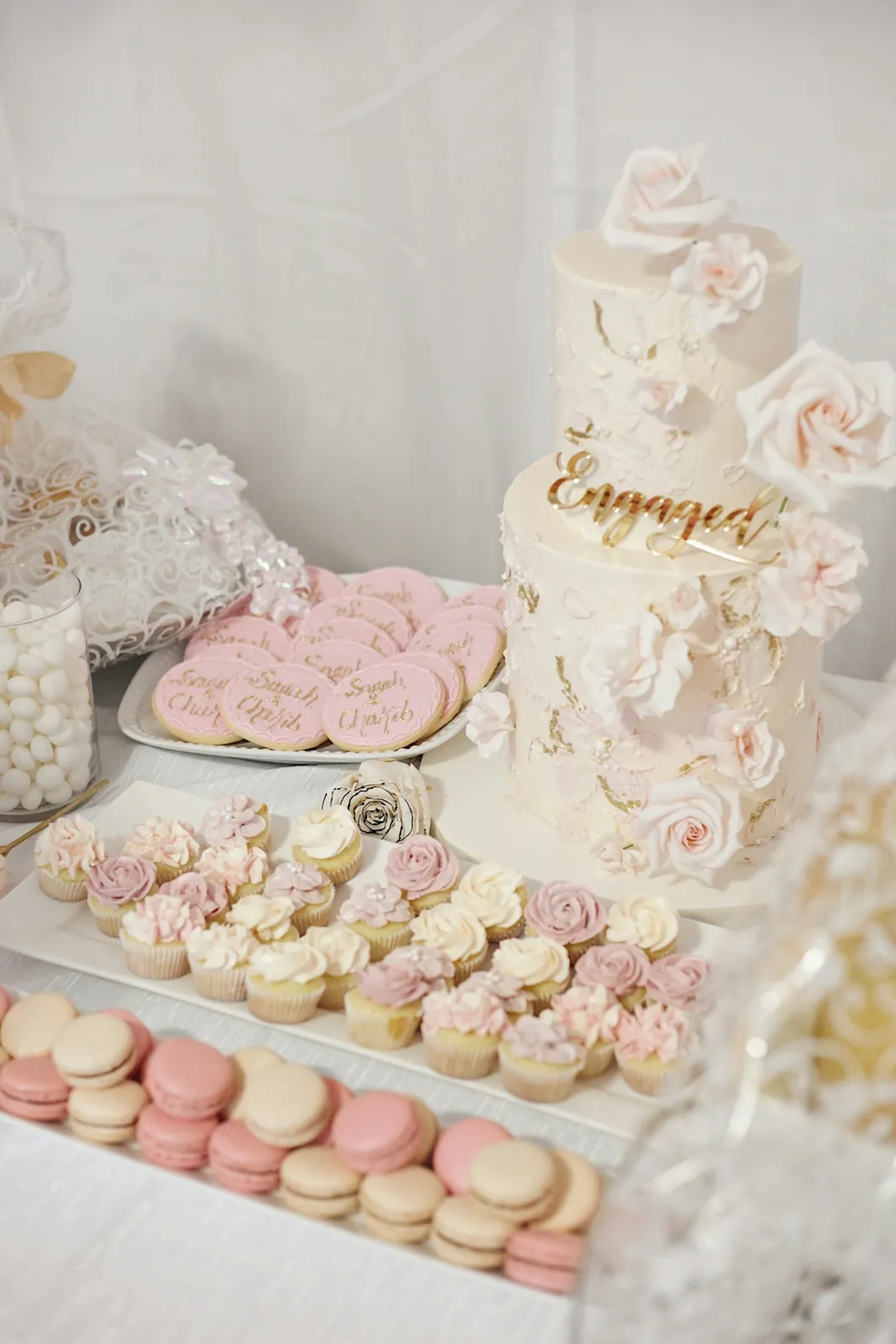 A dessert table of cupcakes, macarons and a celebration cake